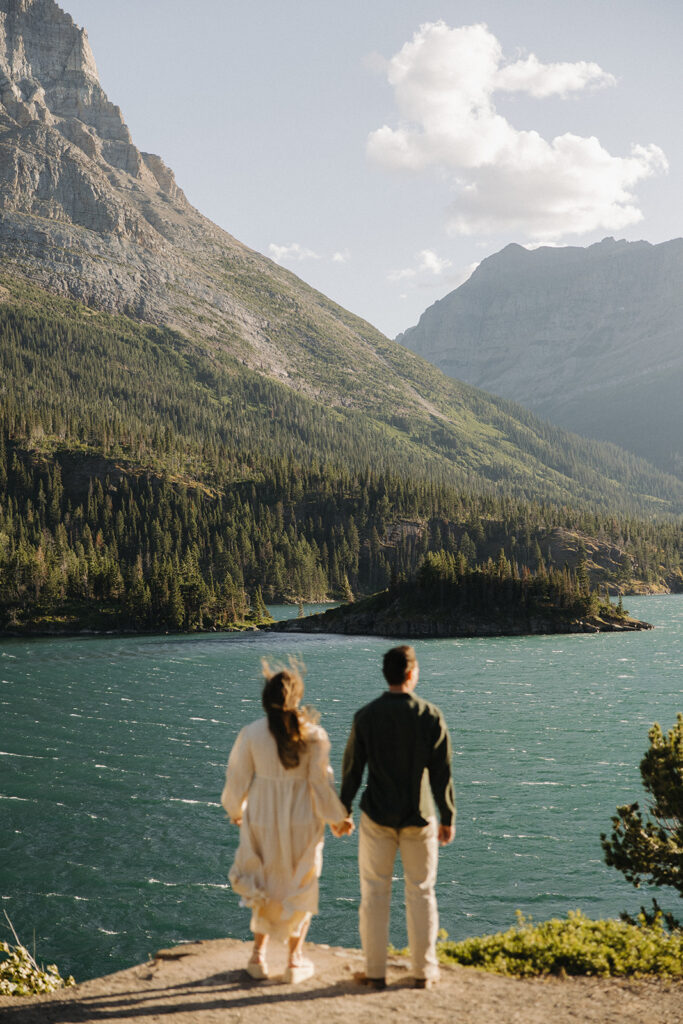 couple holds hands at windy Glacier National Park engagement
