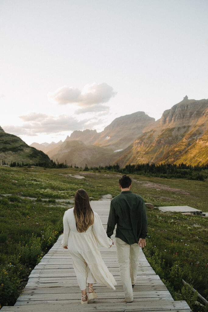 couple walks together at Glacier National Park sunset engagement