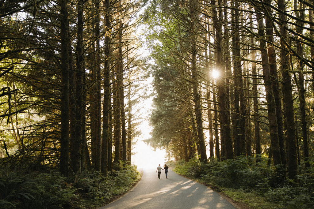 couple walks through sunset woods along Oregon coast