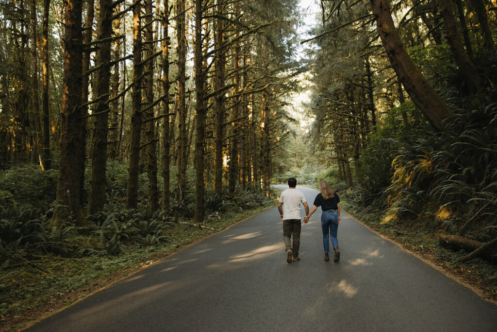 couple walks holding hands through sunset woods