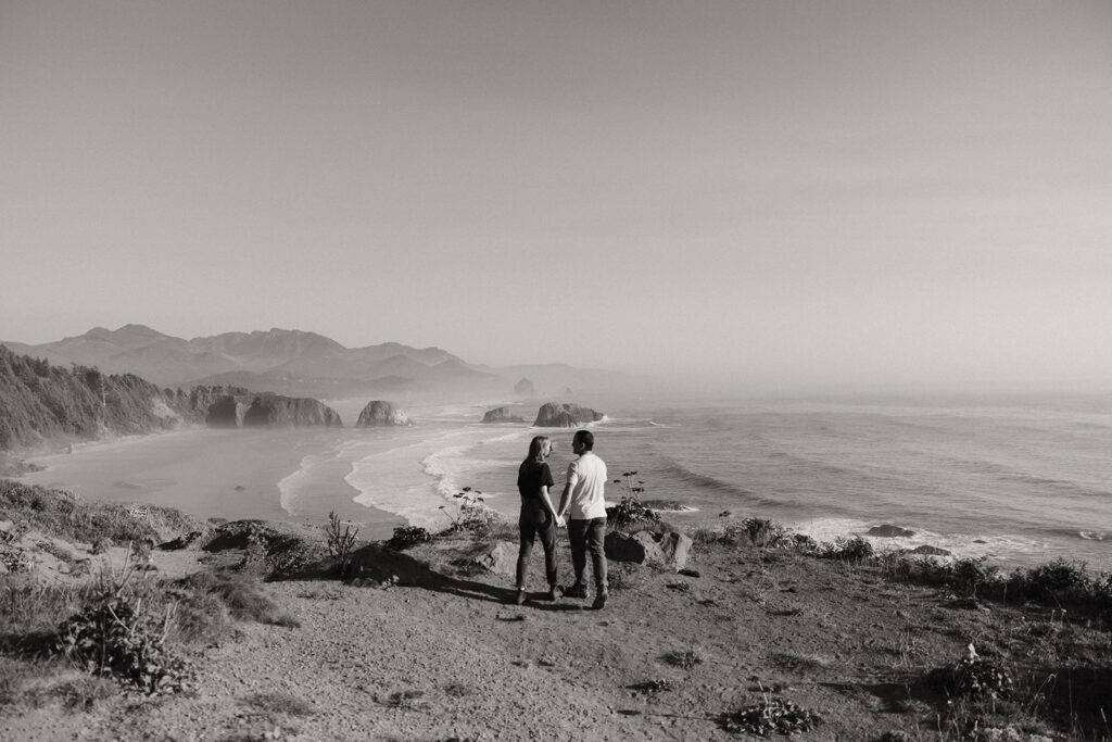 couple holds hands overlooking Oregon coast 