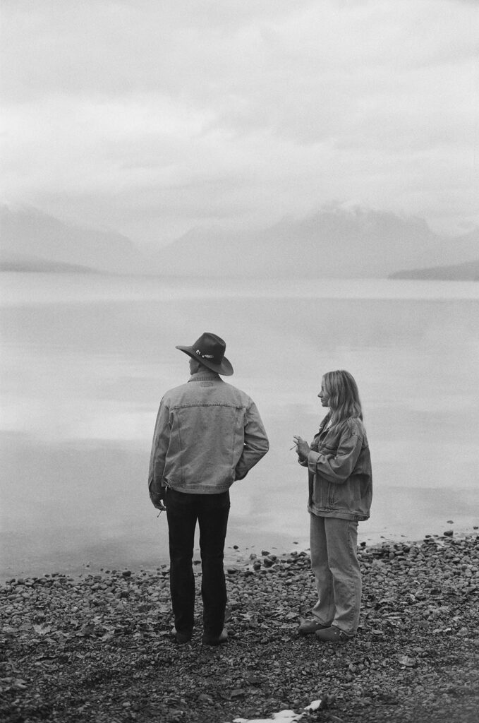 couple stands beside lake with film photography on 35mm