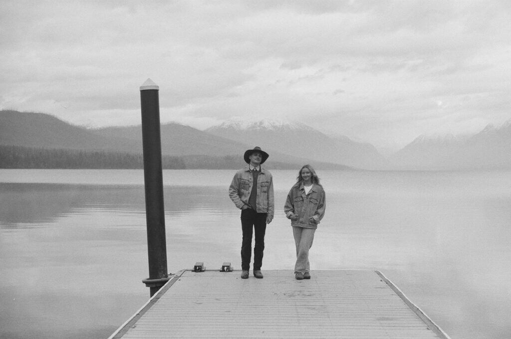 couple stands on pier at Glacier National Park engagement