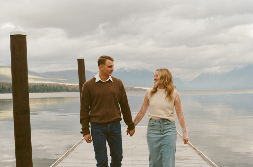 couple walks holding hands on pier with film photography on 35mm