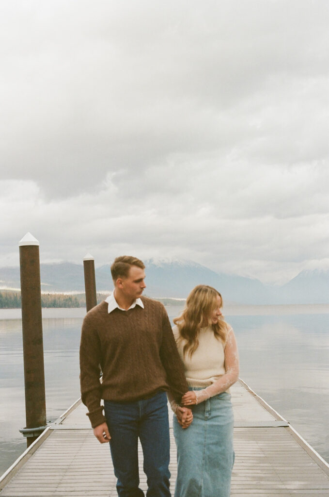 couple walks on pier with film photography on 35mm
