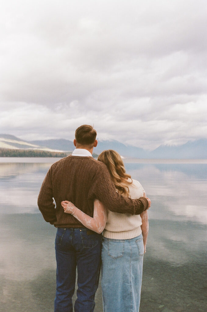 couple embraces on pier at Glacier National Park engagement