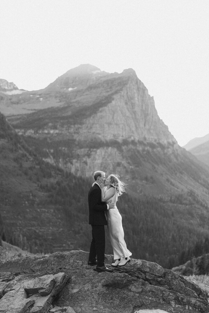 Couple stands on rock in Glacier National Park