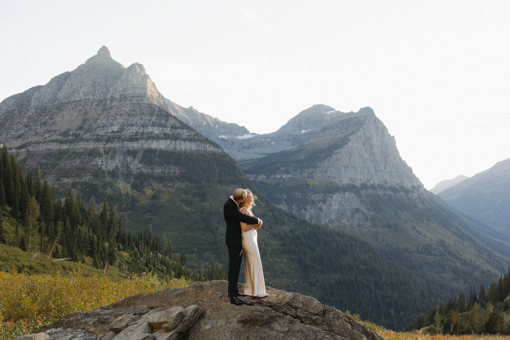 Couple stands on rock in Glacier National Park