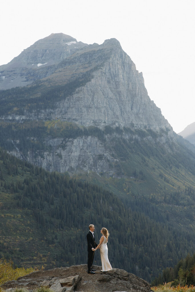 Couple stands on rock in Glacier National Park