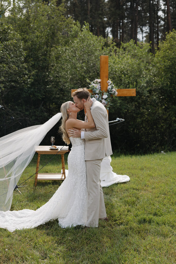 bride and groom share first kiss at montana wedding venue