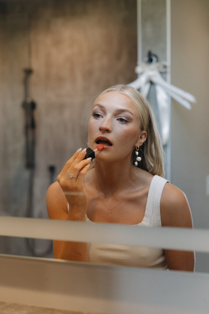 bride putting lipstick on in mirror