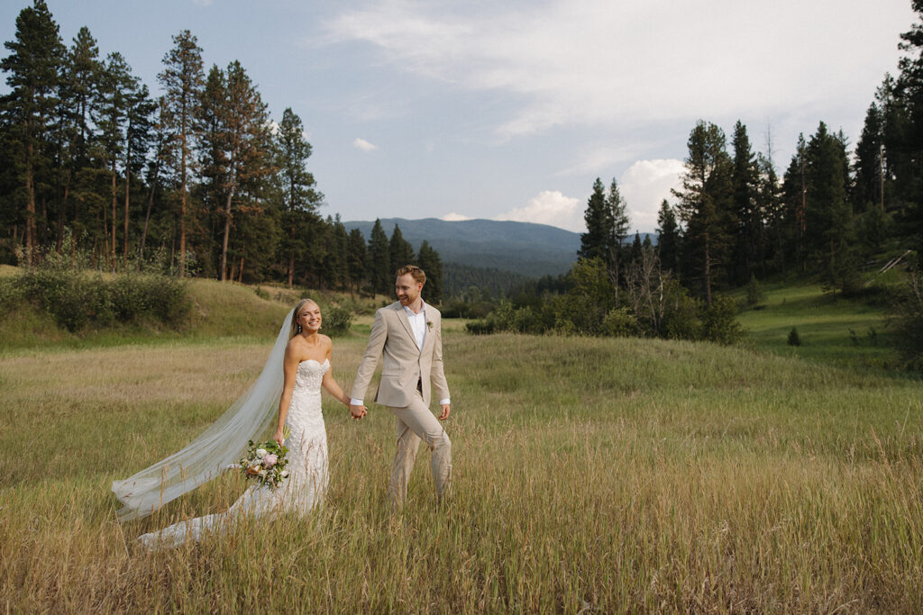 couple walking in field at a montana wedding venue