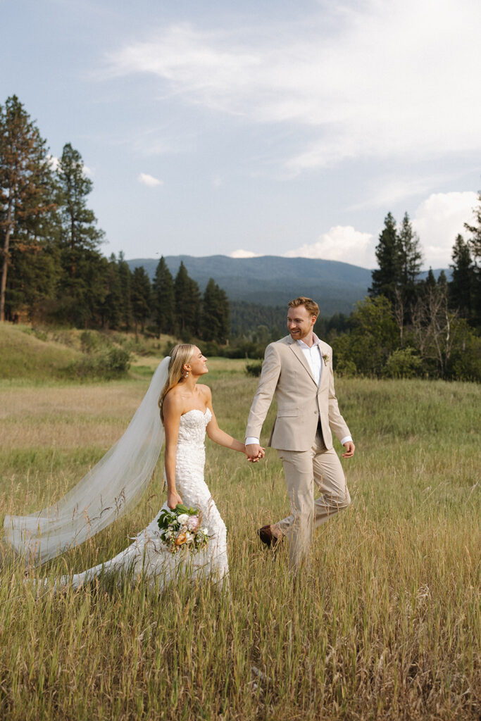 bride and groom walking through field at montana wedding venue