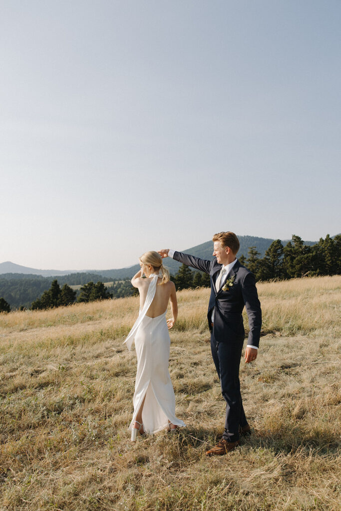 bride and groom walk through field at montana intimate wedding