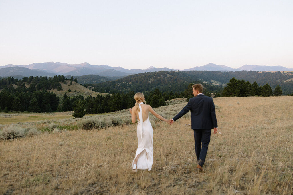 bride and groom walk through field