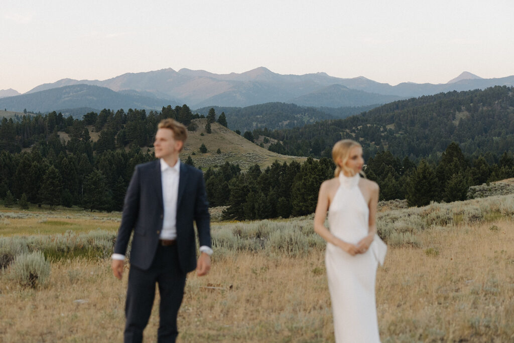 bride and groom walking through field on mountaintop