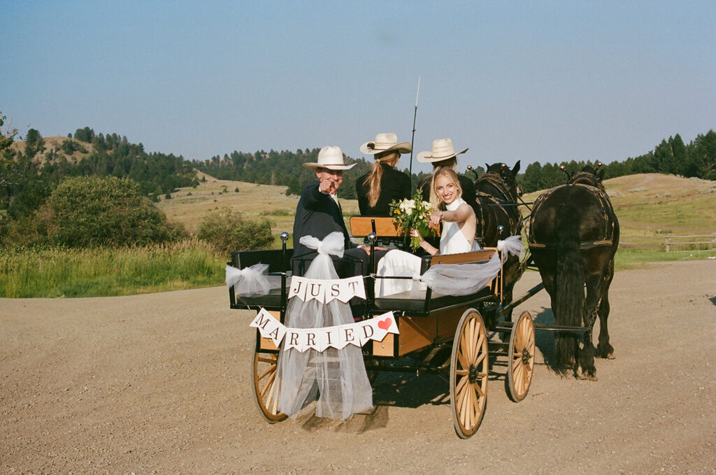 35mm film of bride and groom ride horse drawn carriage at montana intimate wedding