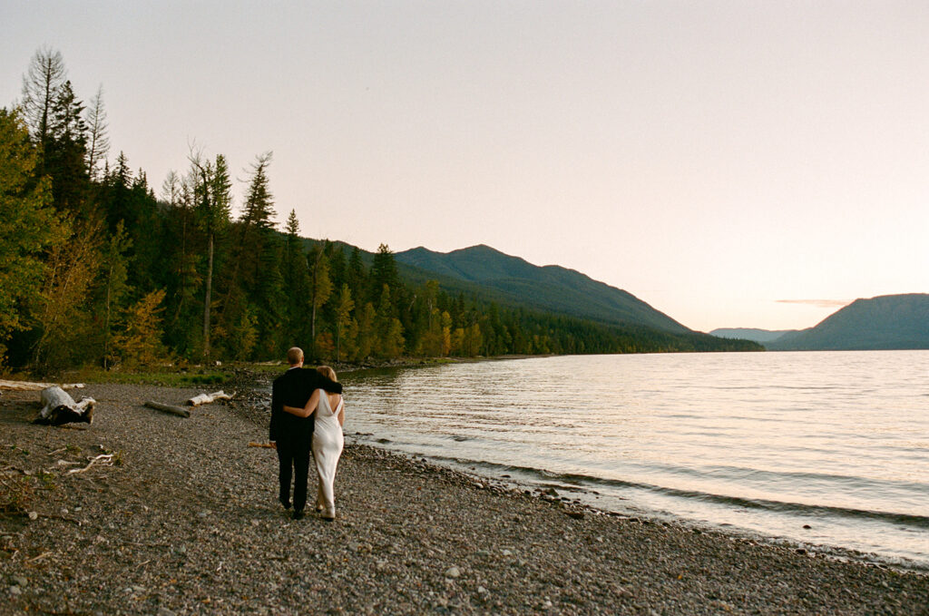 Couple walks along shore of lake in Glacier National Park