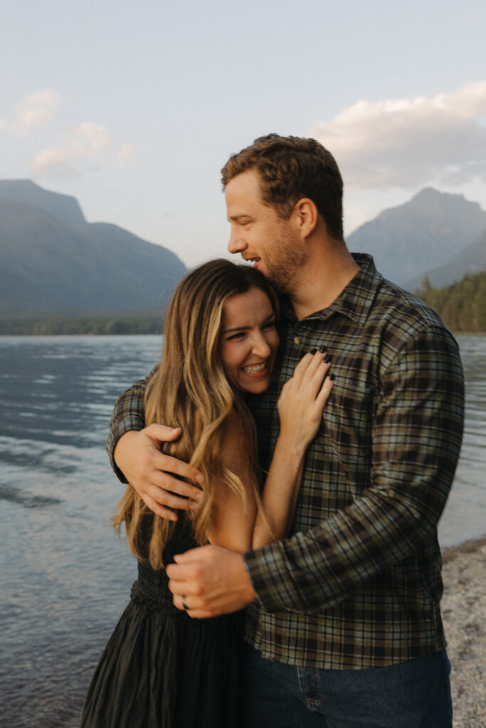 Couple hugs next to Lake McDonald