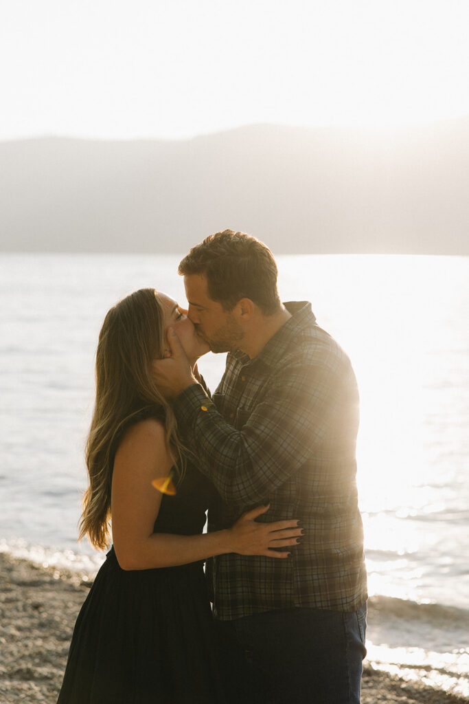 couple kisses on shore of Lake McDonald