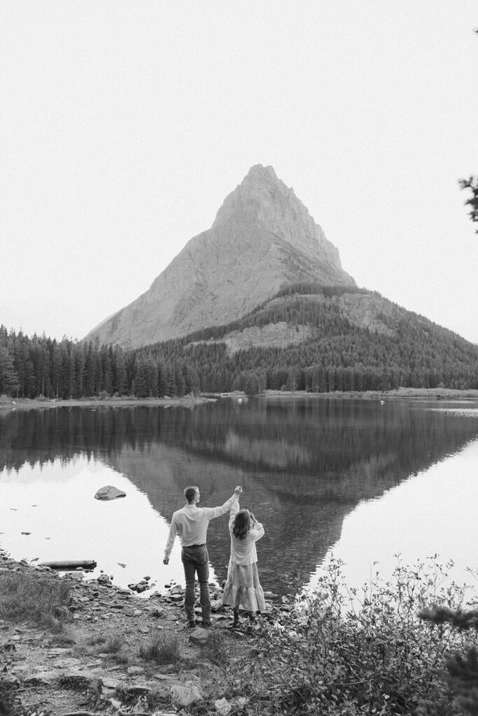 Black and white image of couple standing at Swiftcurrent Lake in Glacier National Park