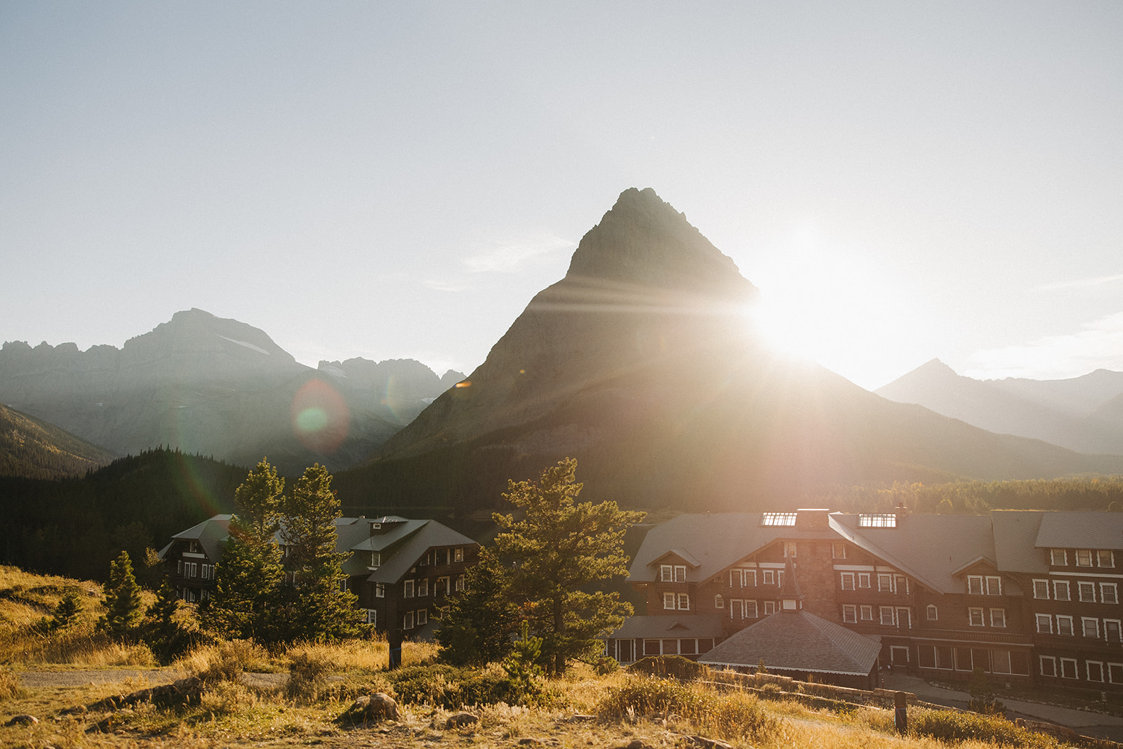 The sun peeking from behind a mountain peak at the Many Glacier Hotel in Glacier National Park