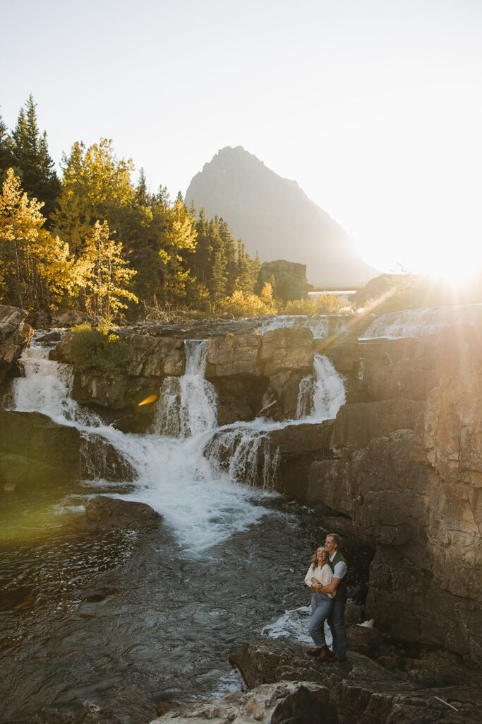 Couple standing at waterfall in Glacier National Park