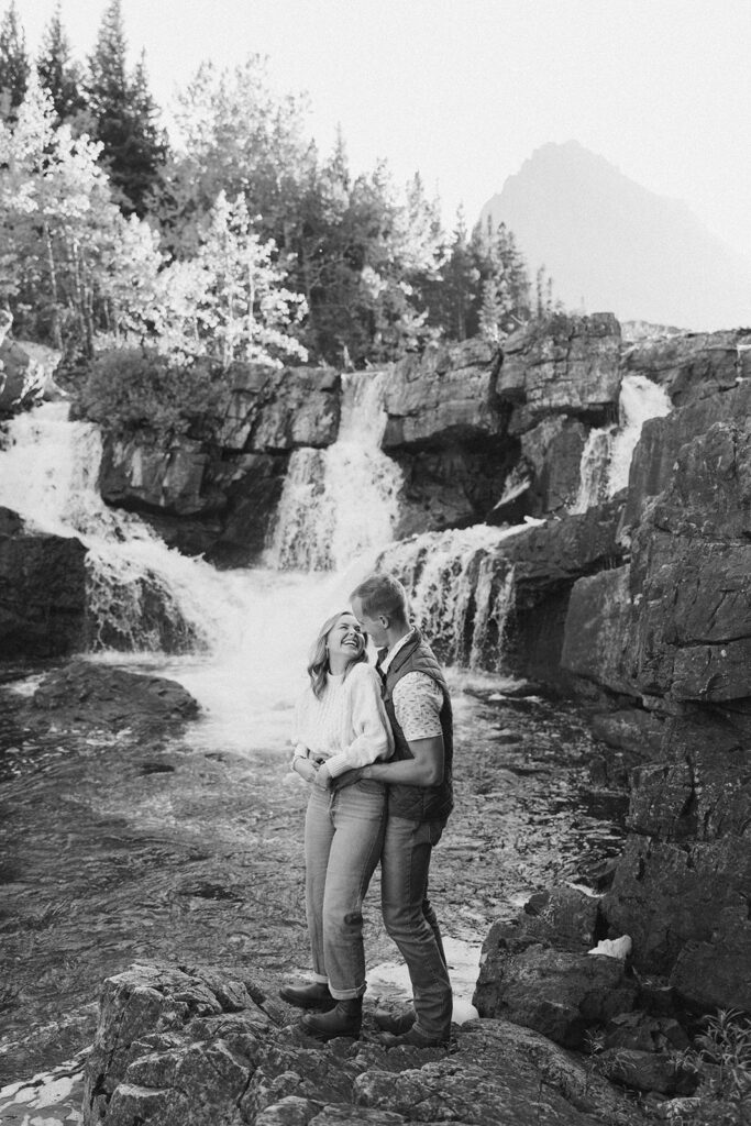 Couple standing and laughing at waterfall in Glacier National Park