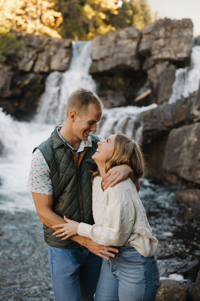 Couple standing and laughing at waterfall in Glacier National Park