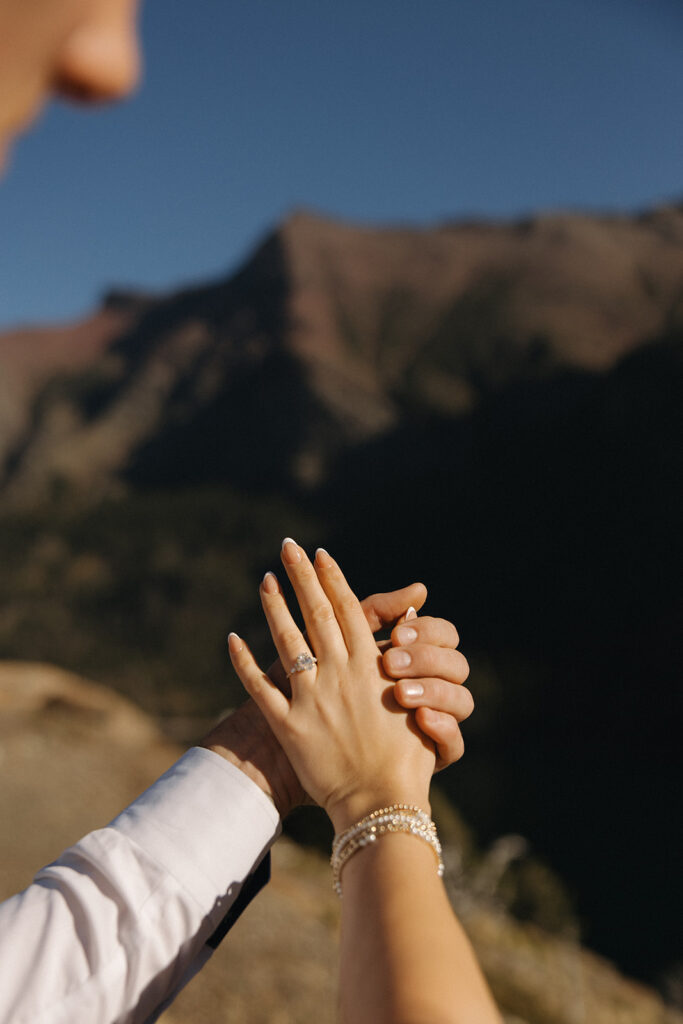 Two hands in the sunlight showcasing the engagement ring