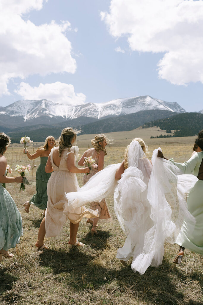 Bridesmaids running in field with mountain views at Three Peaks Ranch Westcliffe Colorado